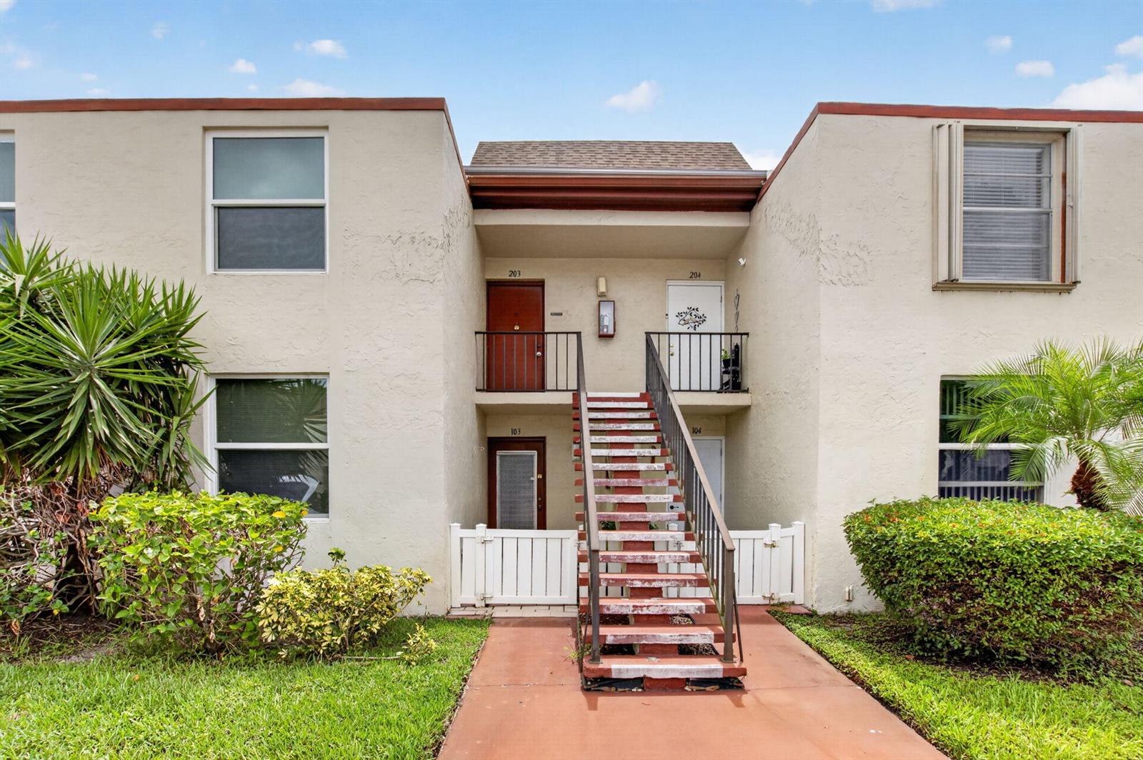 A two-story apartment building exterior features a central staircase leading to upper-level units — 11 Willowbrook Lane # 204, Delray Beach FL 33446, DELRAY BEACH, FL