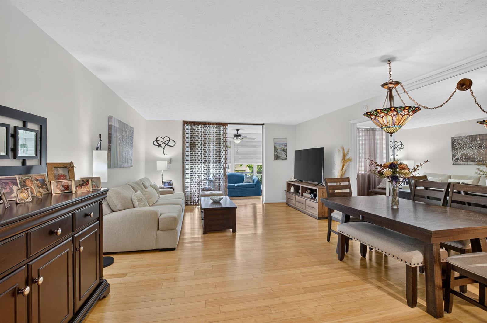 An open-concept living and dining room with hardwood floors, a stained-glass chandelier, and a balcony — 11 Willowbrook Lane # 204, Delray Beach FL 33446, DELRAY BEACH, FL