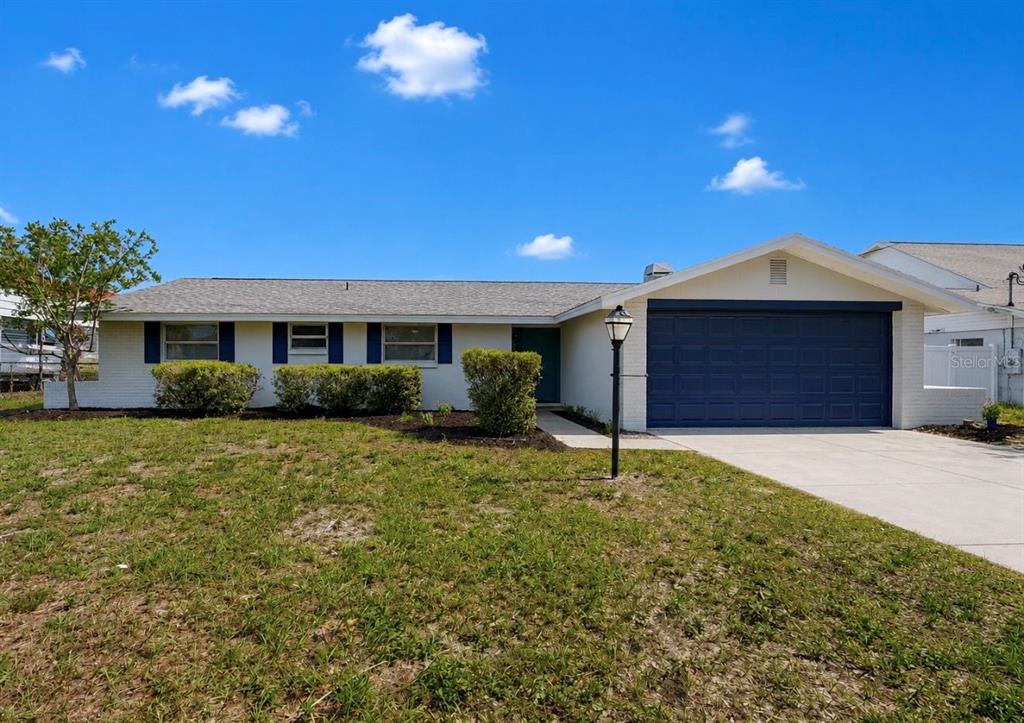 A single-story house with a white brick exterior, blue garage door, and a front lawn — 617 GOLF AND SEA BOULEVARD, APOLLO BEACH, FL