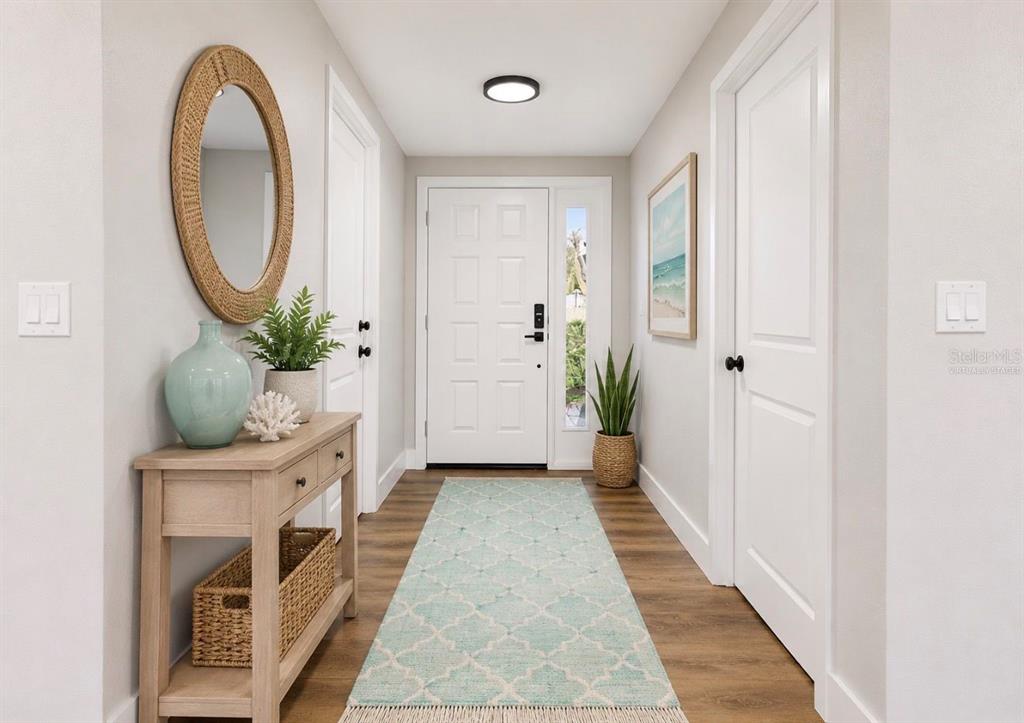 A bright entryway features a light wood console table, a patterned runner, and white doors — 617 GOLF AND SEA BOULEVARD, APOLLO BEACH, FL