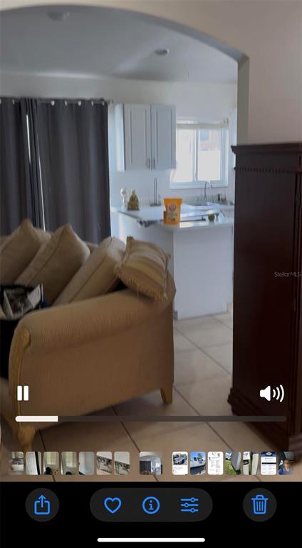 A living room with a beige sofa opens into a kitchen with white cabinets — 136 KNOTTS LANE, KISSIMMEE, FL