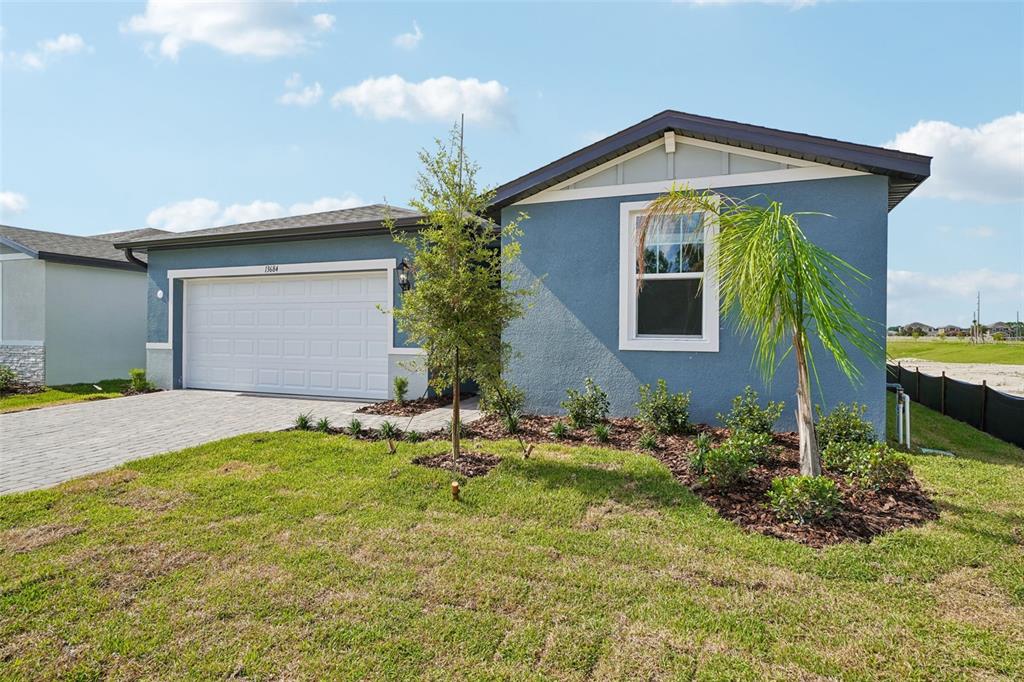 A blue single-story house with a two-car garage and a small palm tree in front — 13684 UMBER FOREST STREET, HUDSON, FL
