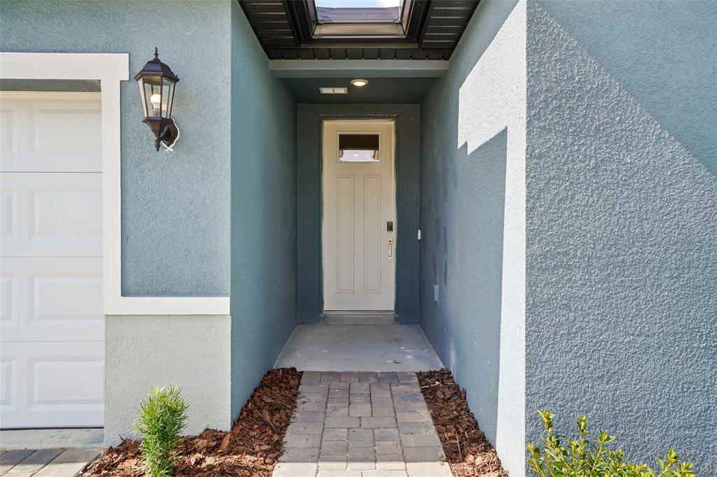 A blue stucco home exterior features a white front door and a brick walkway — 13684 UMBER FOREST STREET, HUDSON, FL