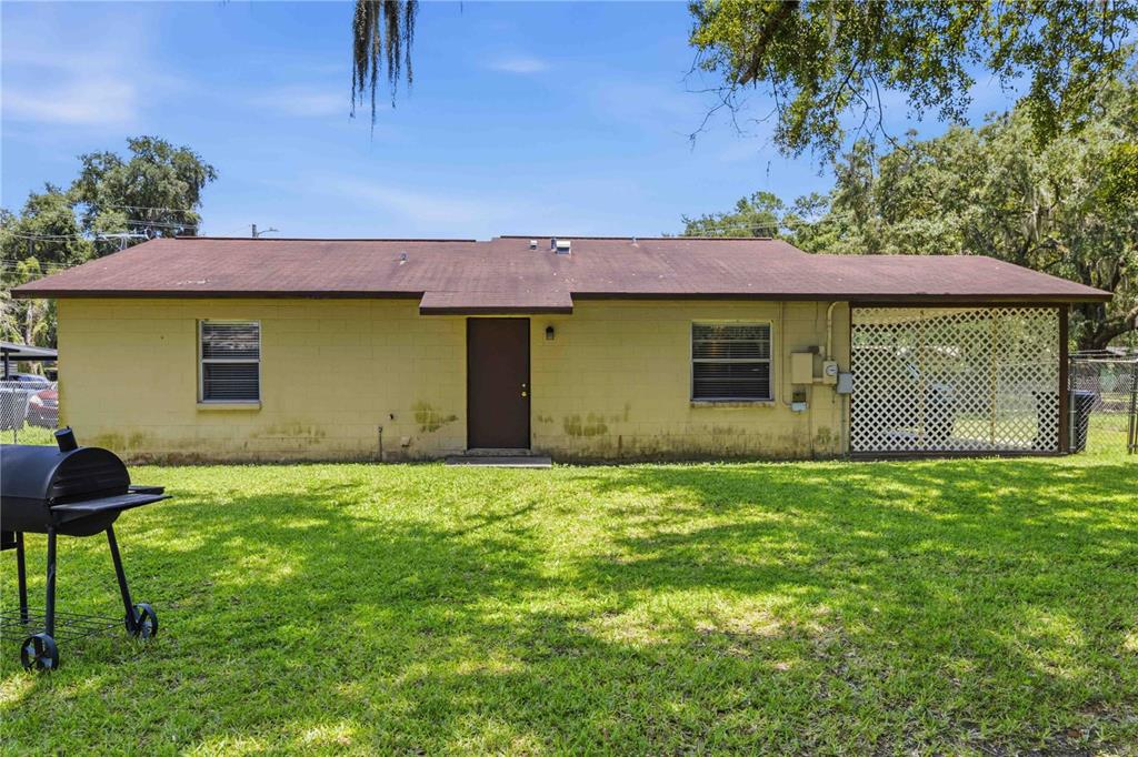 The exterior of a single-story house features a yellow block wall and a covered patio — 2113 OAKVIEW LANE, PLANT CITY, FL