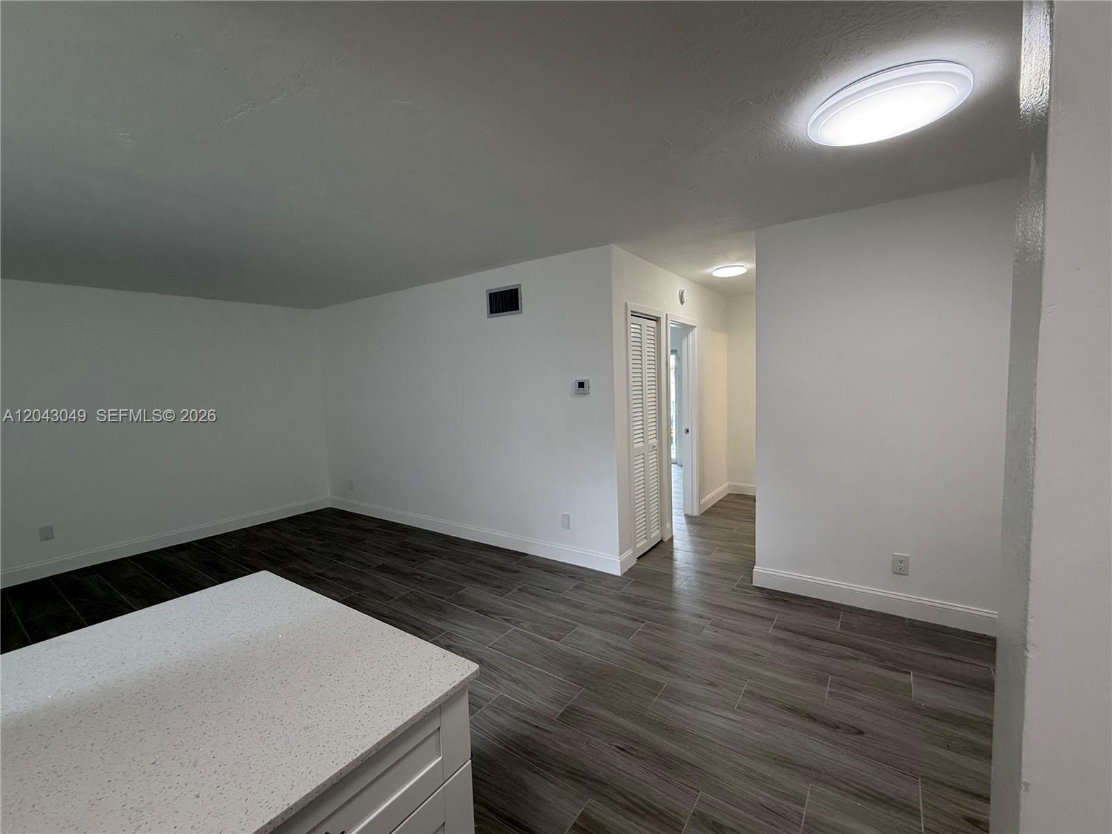 An interior view shows a room with white walls, gray wood-look flooring, and recessed lighting — 1895 Venice Park Dr # B6, Miami FL 33181, MIAMI, FL