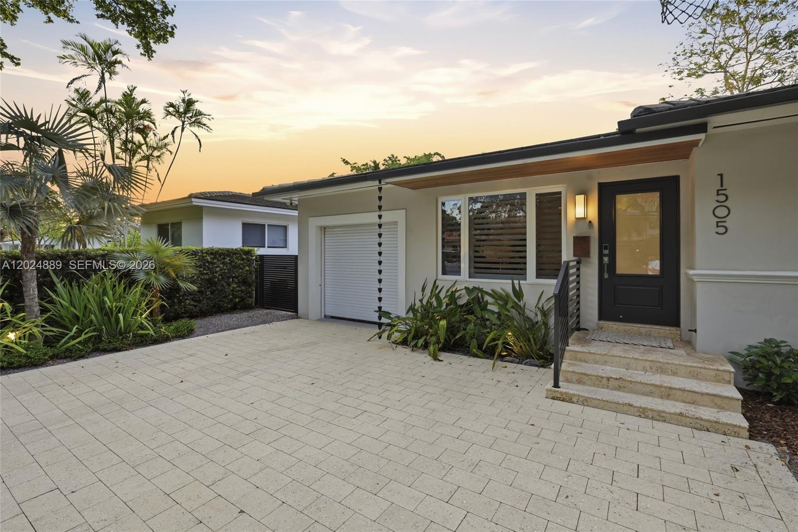 The exterior of a single-story house features a paved driveway, a garage, and stone steps — 1505 Robbia Ave, Coral Gables FL 33146, CORAL GABLES, FL