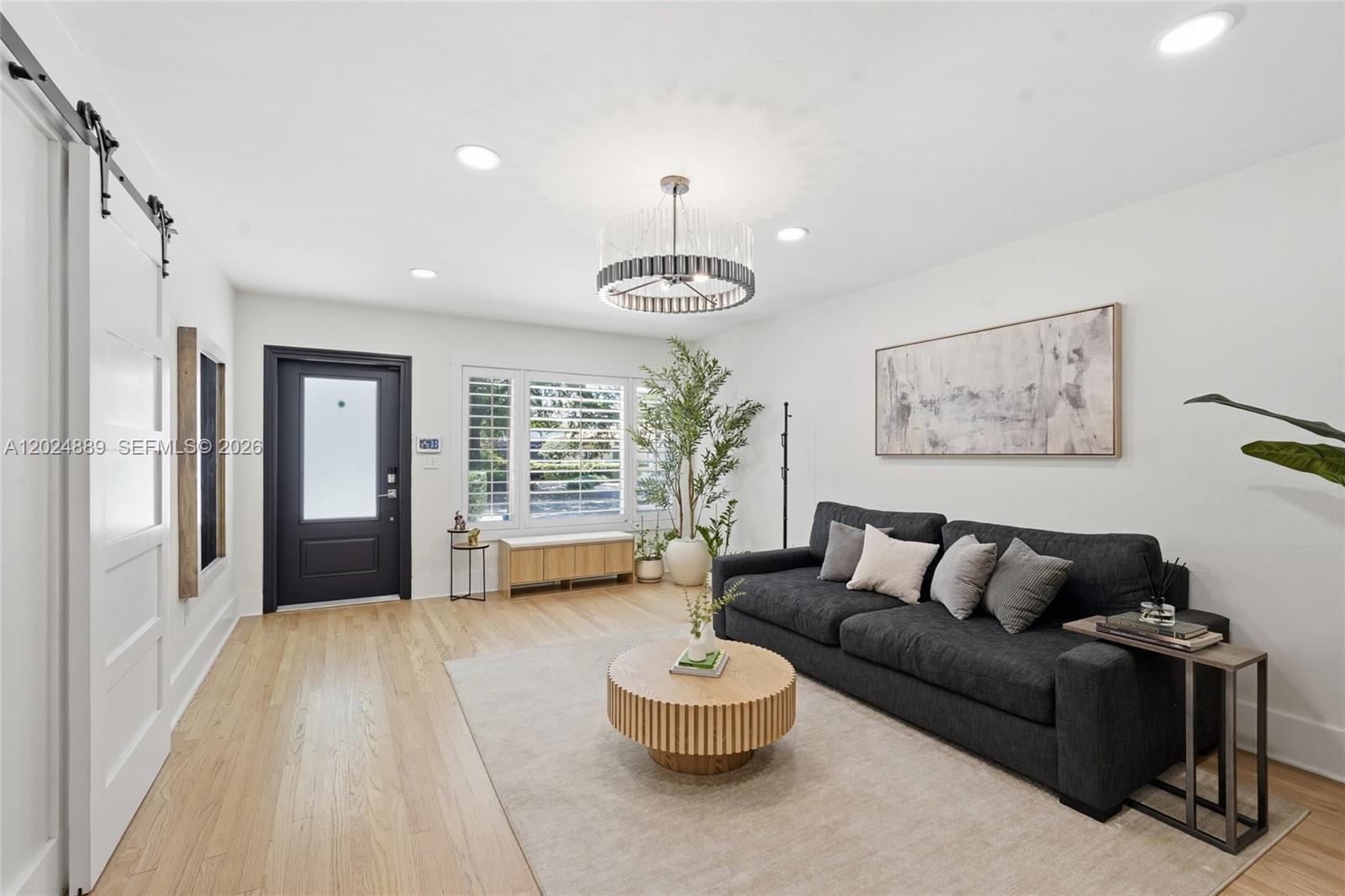 A living room features a dark gray sofa, a round wooden coffee table, and light flooring — 1505 Robbia Ave, Coral Gables FL 33146, CORAL GABLES, FL