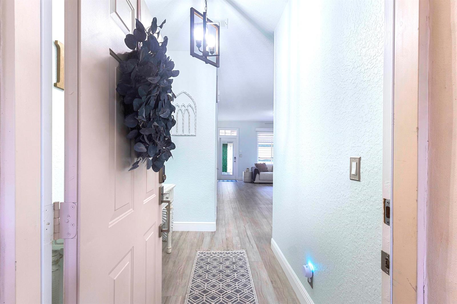 A view through an open front door into a hallway with wood-look flooring — 8070 Murano Circle, Palm Beach Gardens FL 33418, PALM BEACH GARDENS, FL