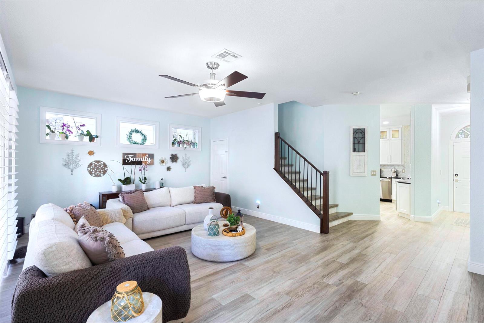 A living room with light blue walls, a sectional sofa, and a staircase — 8070 Murano Circle, Palm Beach Gardens FL 33418, PALM BEACH GARDENS, FL