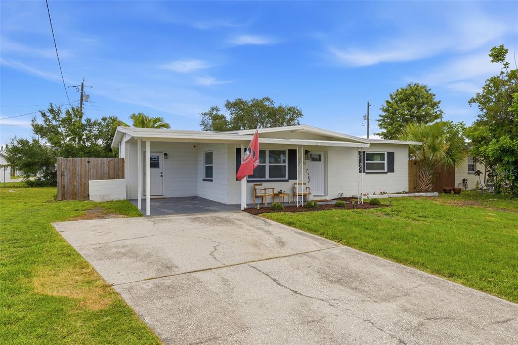 A single-story white house with a carport and a concrete driveway under a blue sky — 9851 52ND STREET N, PINELLAS PARK, FL