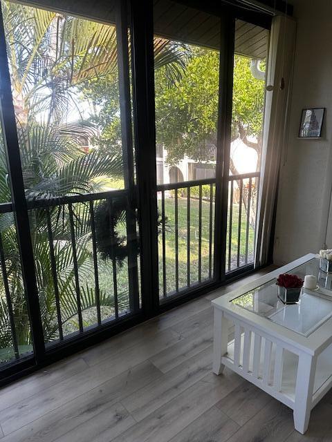 A living room with wood-look flooring, a white coffee table, and sliding glass doors to a balcony — 441 Pine Glen Lane # 2, FL 33463, FL
