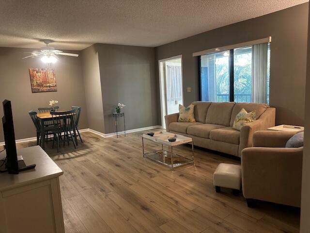 A living and dining area with wood-look flooring, a beige sofa, and a ceiling fan — 441 Pine Glen Lane # 2, FL 33463, FL