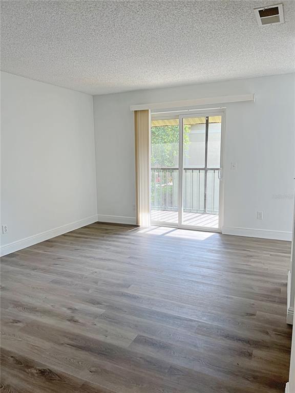 An empty room with light gray walls, wood-look flooring, and a sliding glass balcony door — 2425 BARLEY CLUB DRIVE UNIT 8, ORLANDO, FL