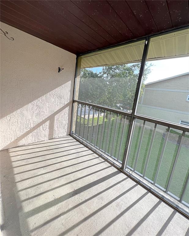 A screened-in balcony with a concrete floor, stucco wall, and dark wood-paneled ceiling — 2425 BARLEY CLUB DRIVE UNIT 8, ORLANDO, FL