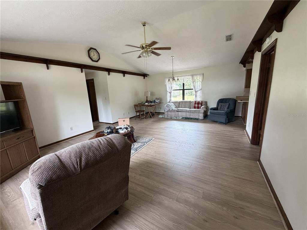 A living room with light wood-look flooring, vaulted ceilings, and a ceiling fan — 2776 NE 31ST PLACE, OCALA, FL