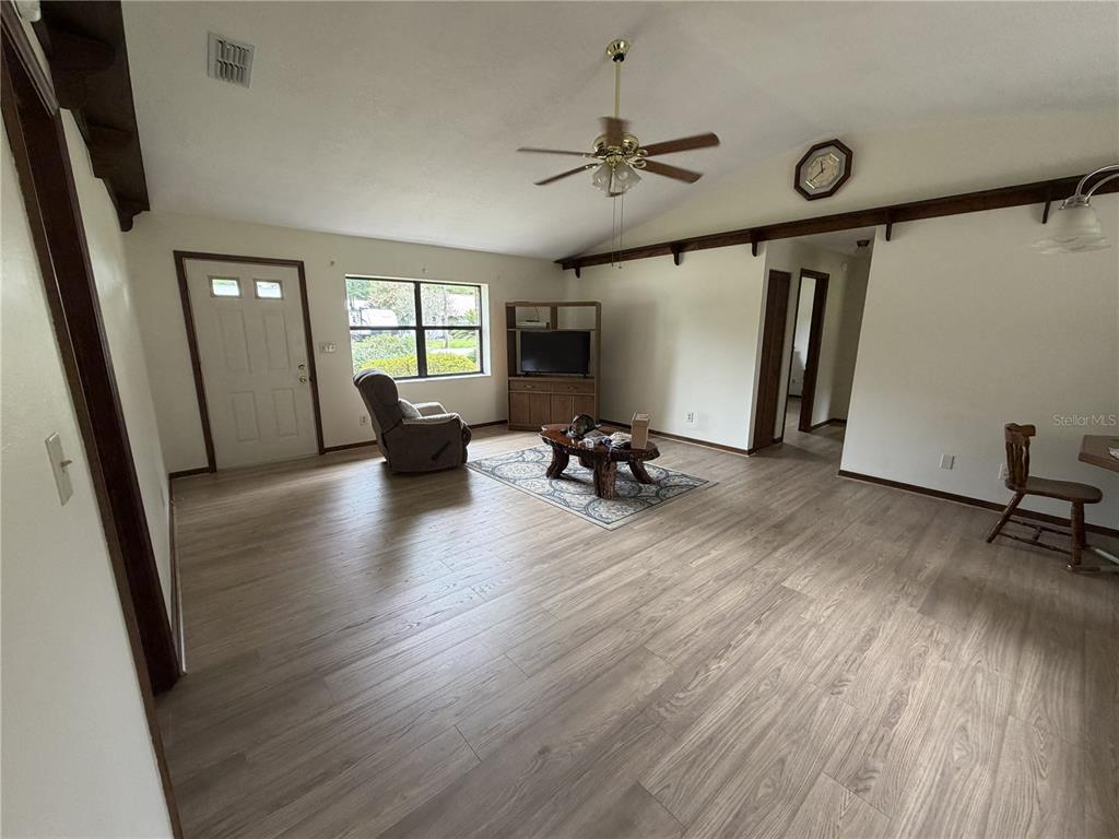 A living room features wood-look flooring, a vaulted ceiling with a fan, and a front door — 2776 NE 31ST PLACE, OCALA, FL
