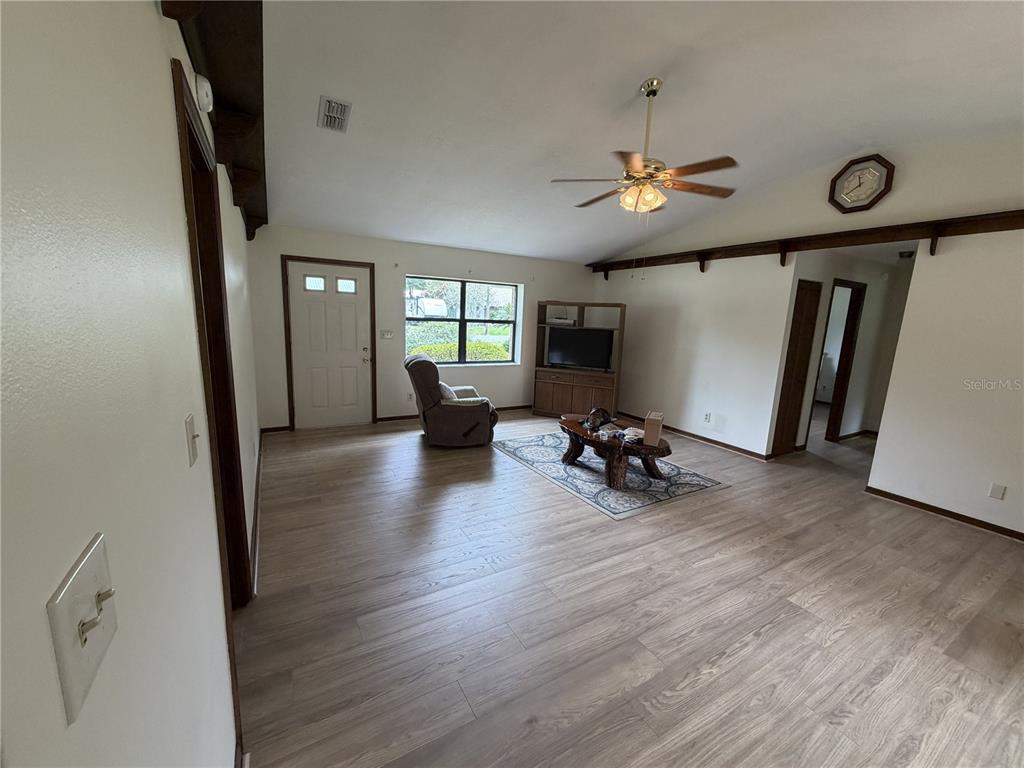 A living room features light wood-look flooring, a ceiling fan, and a large window — 2776 NE 31ST PLACE, OCALA, FL