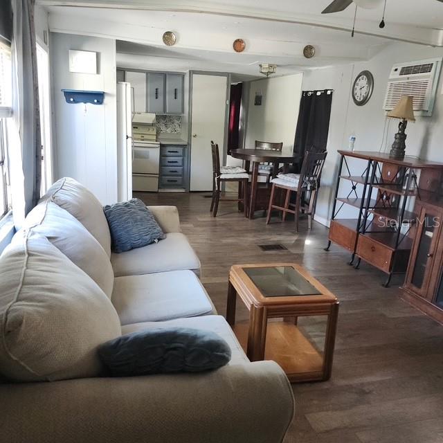 A living room with a light-colored sofa, wood-look flooring, and an adjacent dining area — 5820 OLIVE DRIVE, NEW PORT RICHEY, FL