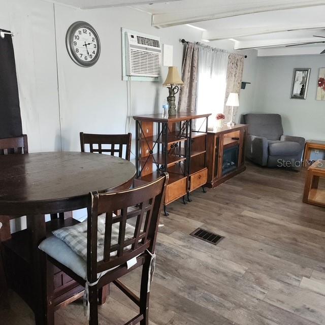 A dining area with a round wooden table sits adjacent to a living room space — 5820 OLIVE DRIVE, NEW PORT RICHEY, FL
