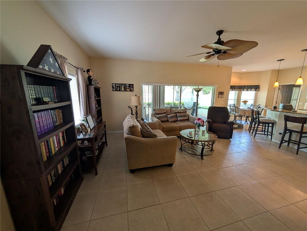 A living room features tile flooring, a ceiling fan, and an open view to the kitchen — 25526 HERITAGE LAKE BOULEVARD, PUNTA GORDA, FL