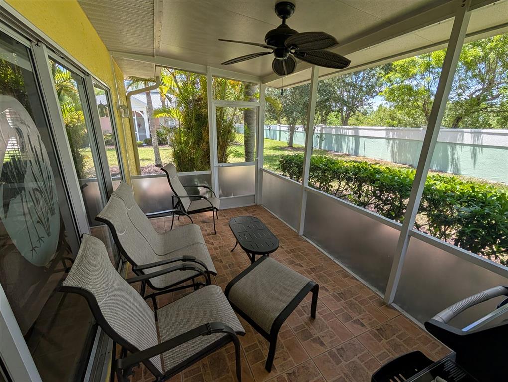 A screened-in patio features tiled flooring, outdoor furniture, a ceiling fan, and a fenced yard — 25526 HERITAGE LAKE BOULEVARD, PUNTA GORDA, FL