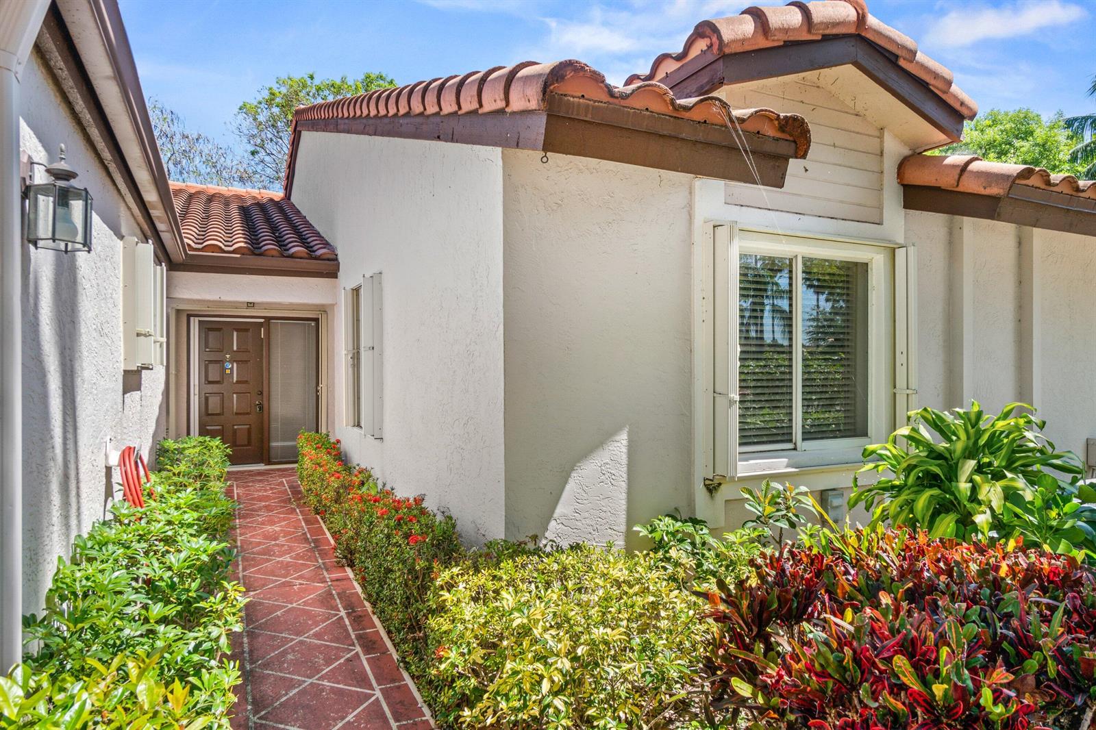 A red-tiled walkway leads to the front door of a stucco home with tile roofing — 6079 Millington Way, Delray Beach FL 33484, DELRAY BEACH, FL
