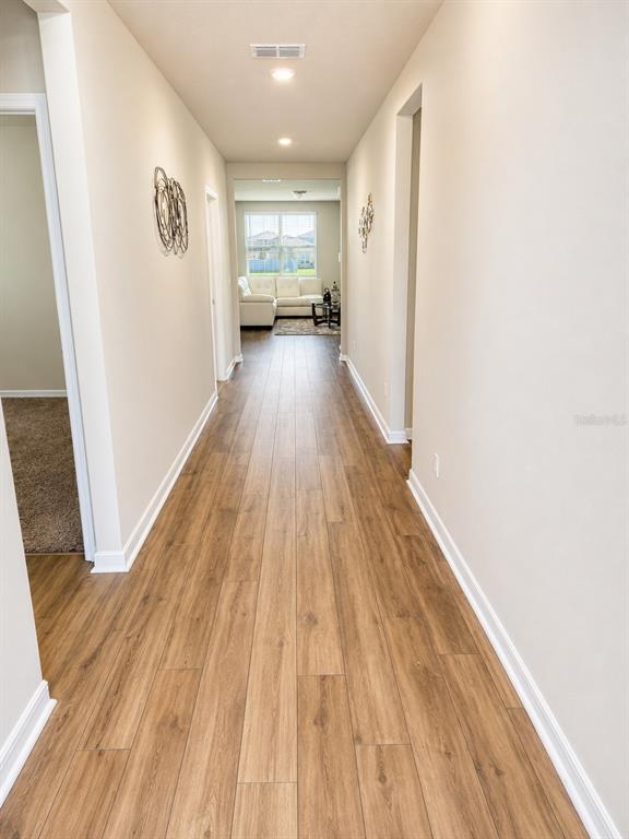 A long hallway with wood-look flooring leads to a living area with a white sofa — 196 TOWNS CIRCLE, HAINES CITY, FL
