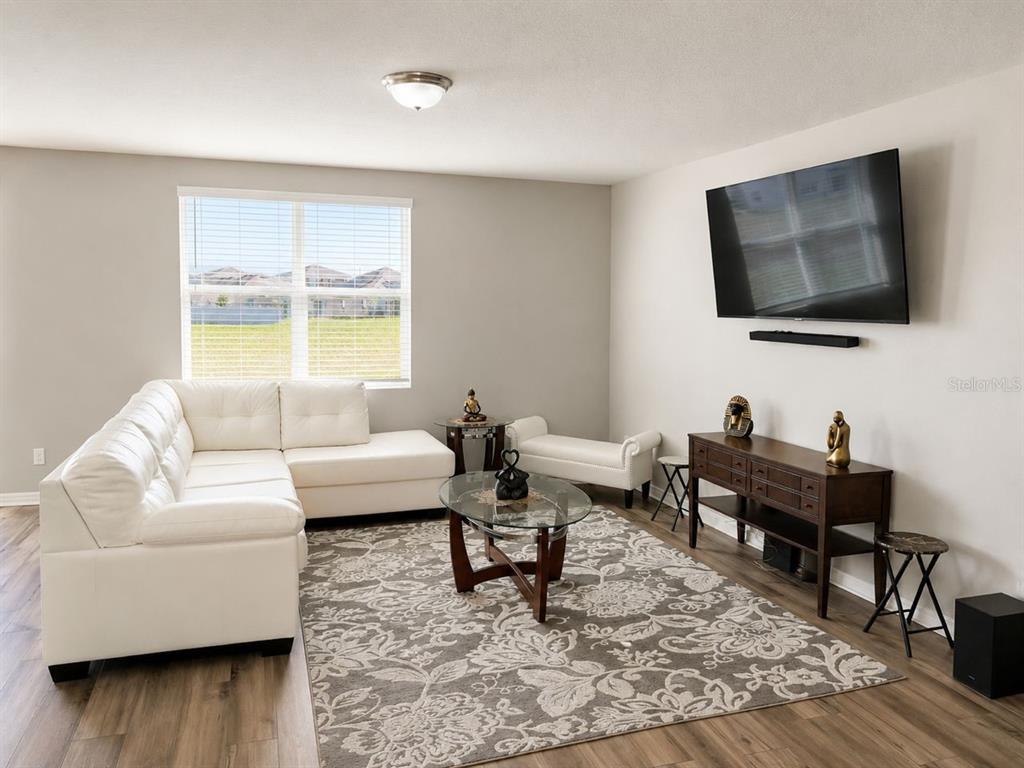 A living room features a white sectional sofa, a patterned rug, and a wall-mounted television — 196 TOWNS CIRCLE, HAINES CITY, FL