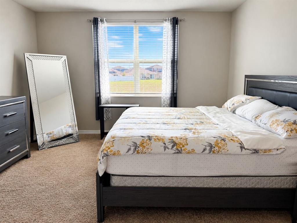 A bedroom features a bed with floral bedding, a large floor mirror, and a window — 196 TOWNS CIRCLE, HAINES CITY, FL