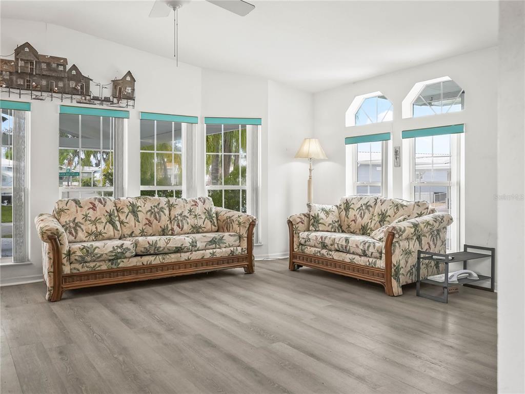A living room features two floral sofas, light wood-look flooring, and multiple windows — 37 SILVER DOCTOR LANE, LAKE WALES, FL