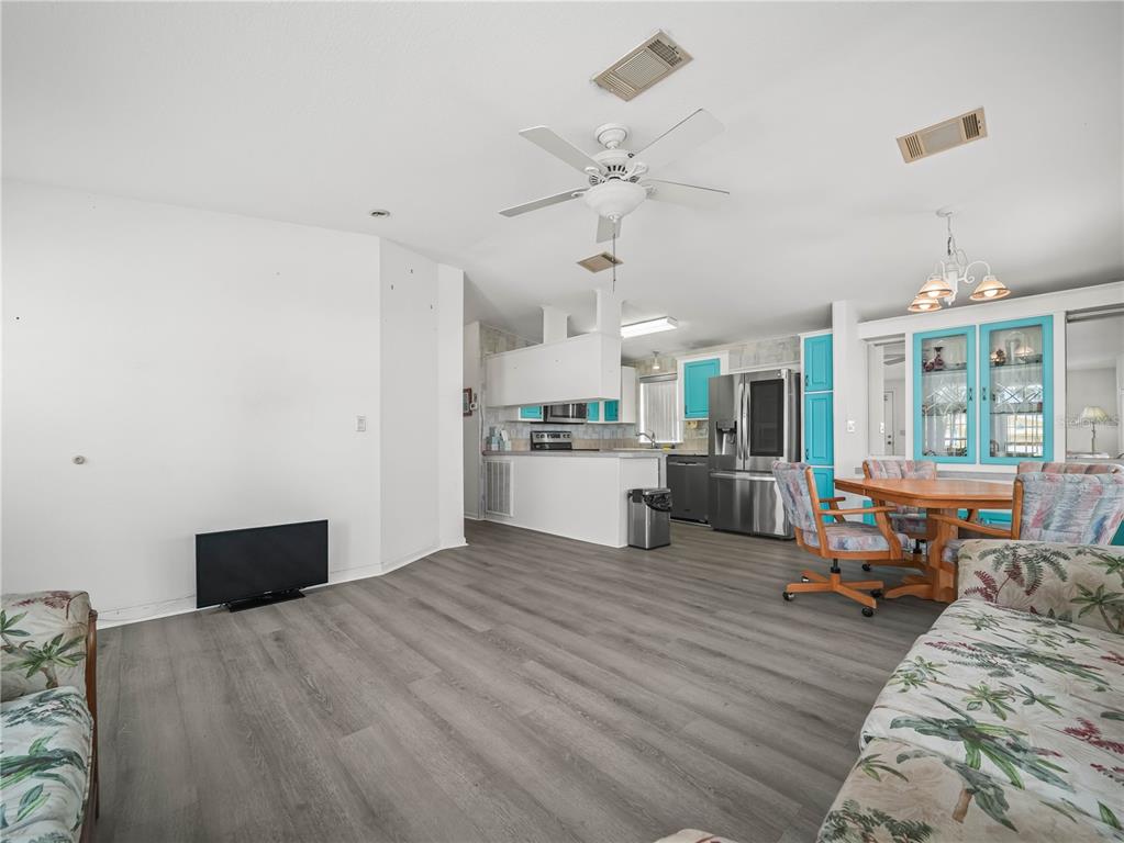 A living and dining area features gray wood-look flooring, white walls, and turquoise cabinet accents — 37 SILVER DOCTOR LANE, LAKE WALES, FL