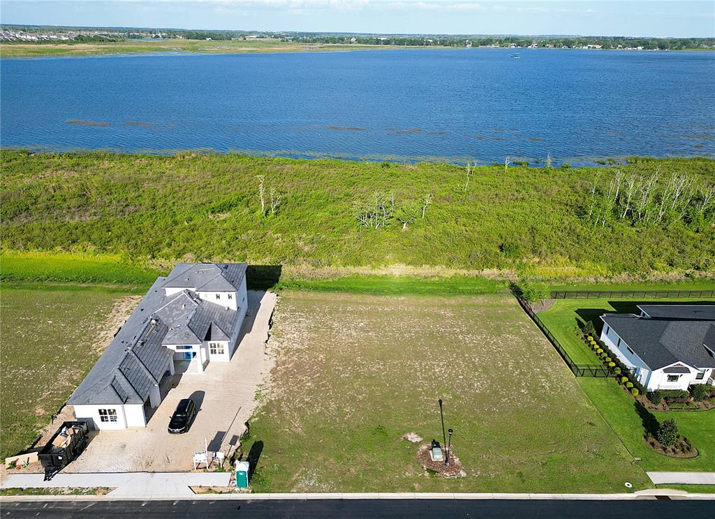 An aerial view shows a vacant residential lot situated between two houses near a lake — 332 CALADIUM AVENUE, LAKE ALFRED, FL