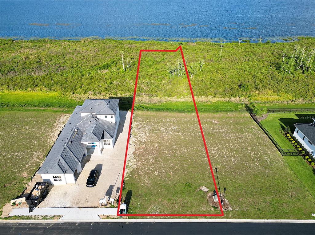 An aerial view shows a vacant rectangular lot outlined in red next to a house — 332 CALADIUM AVENUE, LAKE ALFRED, FL