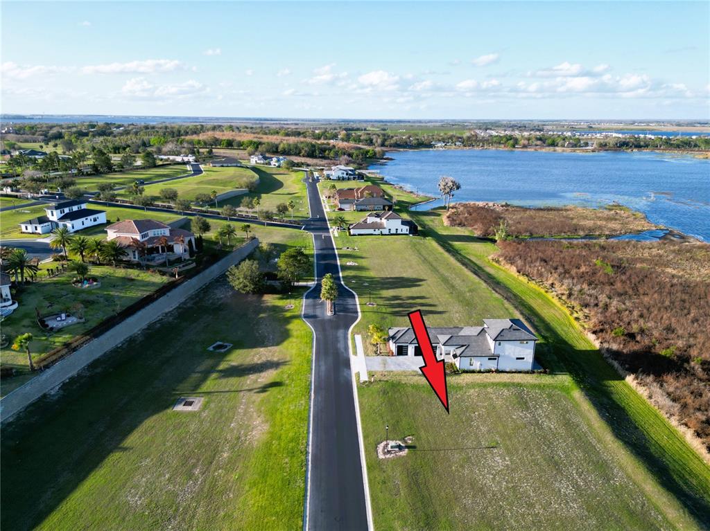 An aerial view shows a vacant residential lot next to a house near a lake — 332 CALADIUM AVENUE, LAKE ALFRED, FL