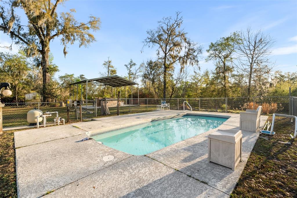 A backyard swimming pool features a patio, outdoor dining set, lounge chairs, and a bar area — 7281 SW 68TH DRIVE, JASPER, FL
