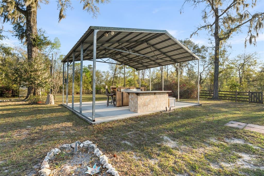 A large workshop with a concrete floor, metal trusses, a loft area, and a lawnmower — 7281 SW 68TH DRIVE, JASPER, FL