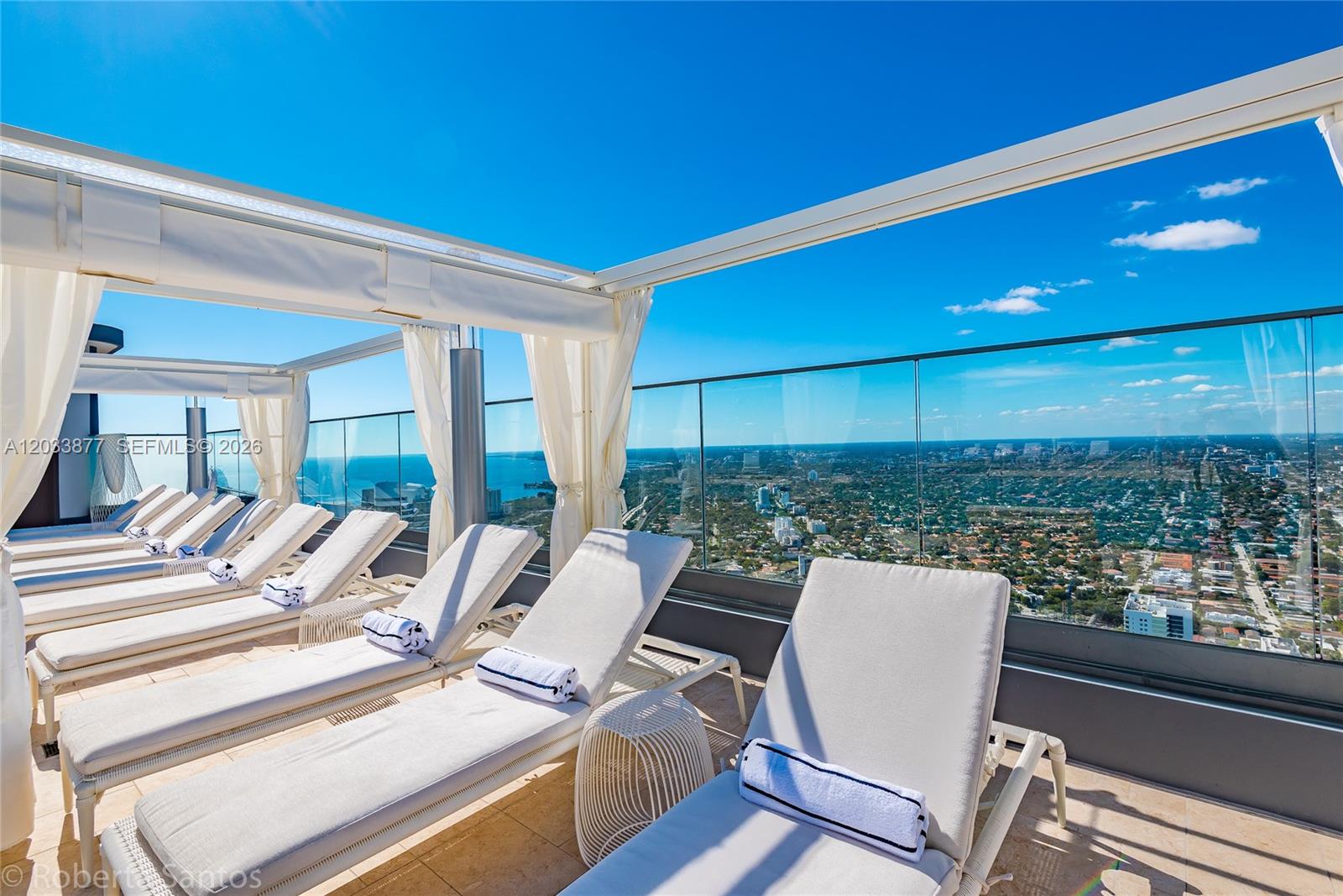 A rooftop terrace features rows of lounge chairs under a canopy overlooking a city view — 1000 Brickell Plaza # 4509, Miami FL 33131, MIAMI, FL