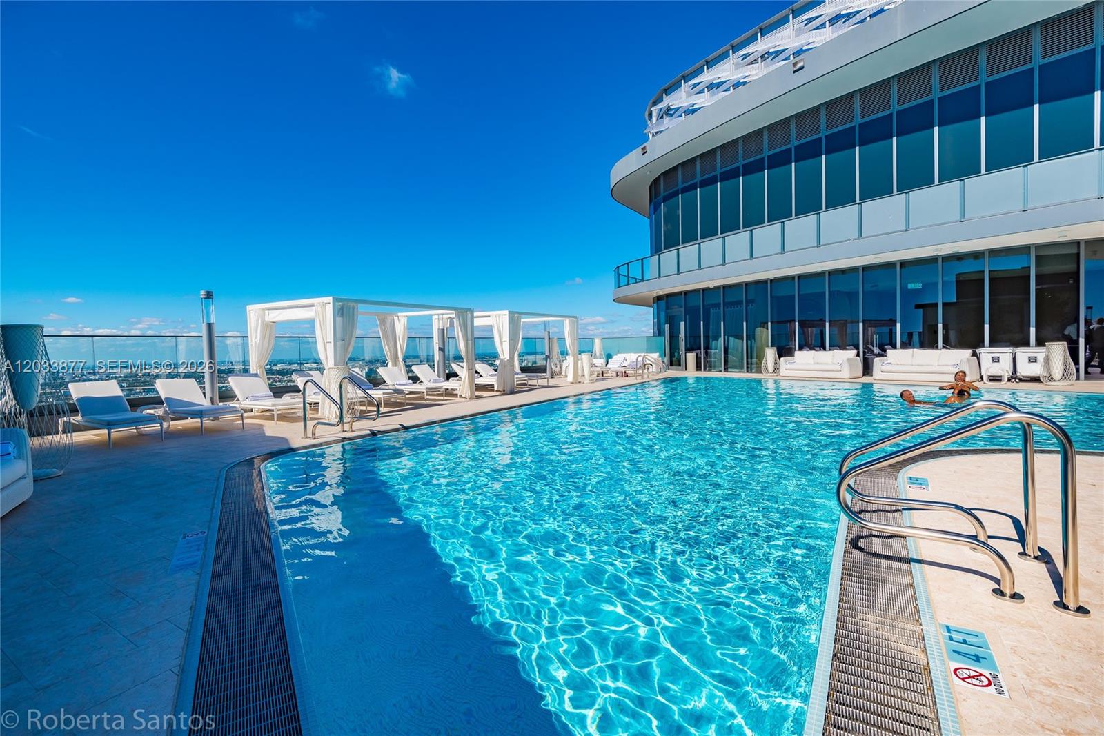 A rooftop swimming pool with lounge chairs and cabanas overlooks a city skyline — 1000 Brickell Plaza # 4509, Miami FL 33131, MIAMI, FL