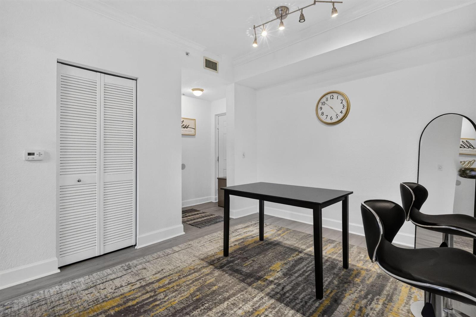A room with white walls, a black table, two chairs, a rug, and a wall clock — 1660 Renaissance Commons Boulevard # 2424, Boynton Beach FL 33426, BOYNTON BEACH, FL