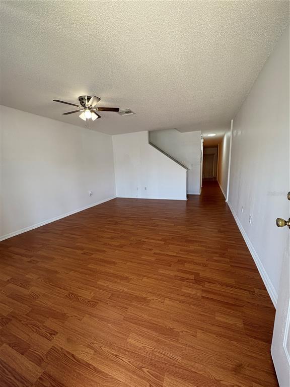An empty living room features wood-look flooring, white walls, and a ceiling fan — 1324 KELRIDGE PLACE, BRANDON, FL