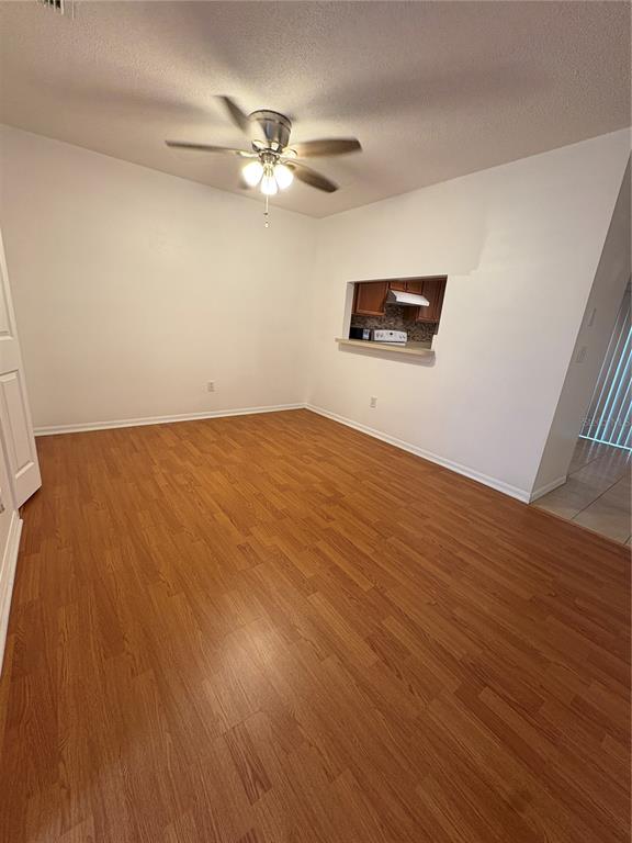 An empty room with wood-look flooring, a ceiling fan, and a pass-through to the kitchen — 1324 KELRIDGE PLACE, BRANDON, FL