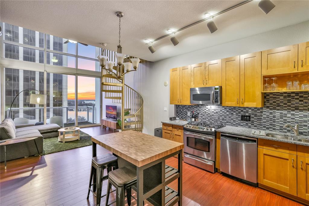 A modern kitchen and living area features a spiral staircase, wood cabinets, and floor-to-ceiling windows — 150 E ROBINSON STREET UNIT 817, ORLANDO, FL
