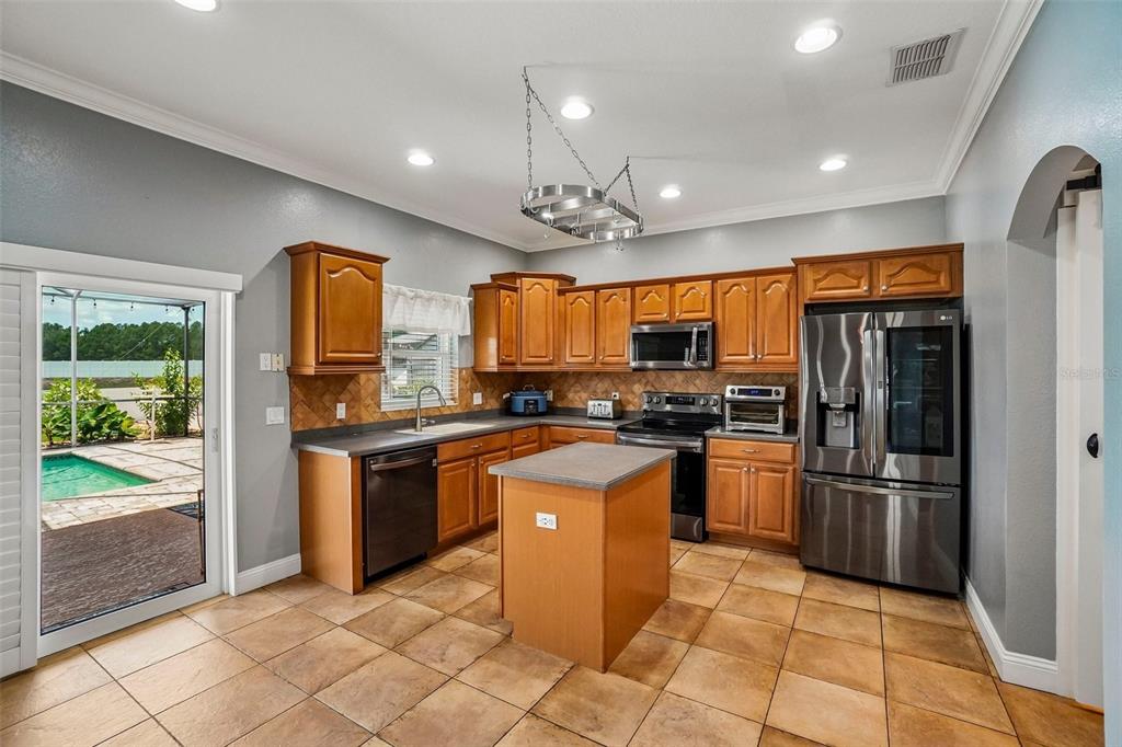 A kitchen with wood cabinets, a center island, stainless steel appliances, and a sliding glass door — 15792 DURANGO CIRCLE, BROOKSVILLE, FL