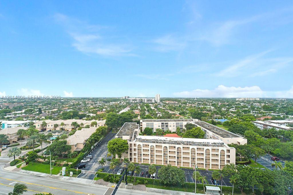 An aerial view shows a multi-story apartment building surrounded by parking lots and suburban greenery — LAUDERDALE BY THE SEA, FL