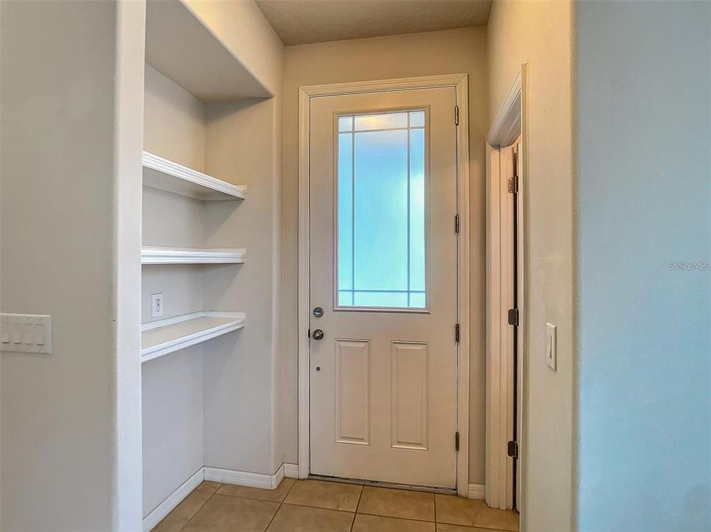 An entryway features a white door with a glass panel and built-in wall shelving — 2932 CELLO LANE, KISSIMMEE, FL