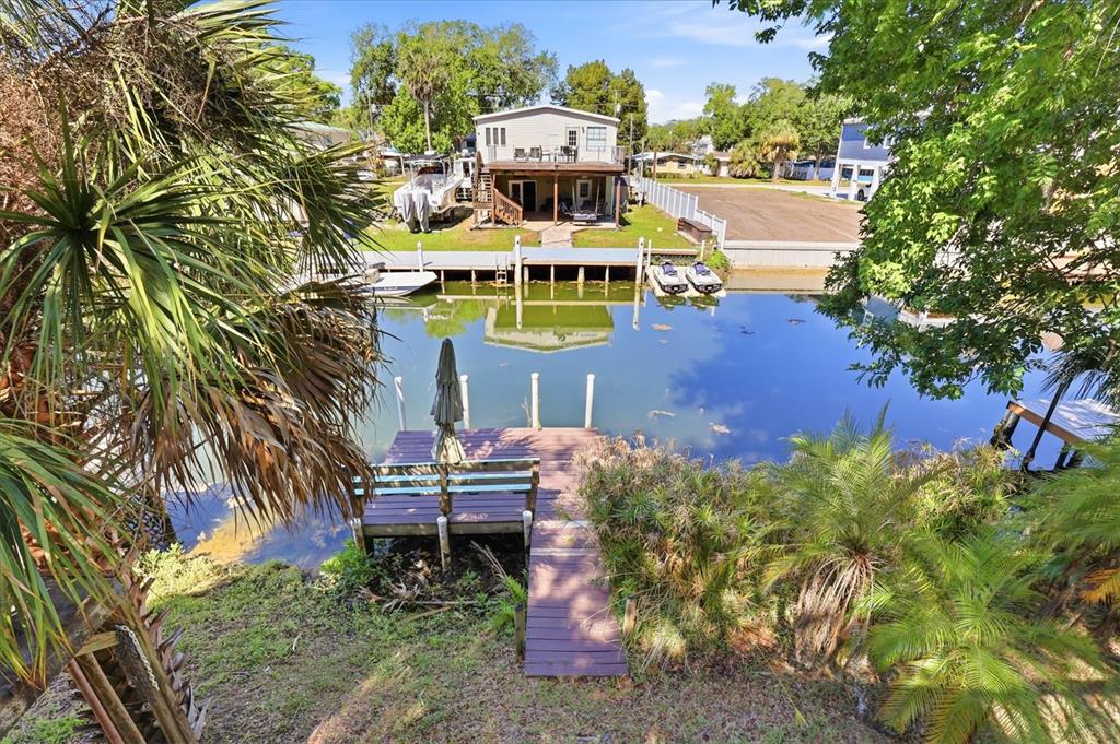 An elevated view of a waterfront property featuring a wooden dock, canal, and residential house — 6169 WAVERLY ROAD, WEEKI WACHEE, FL