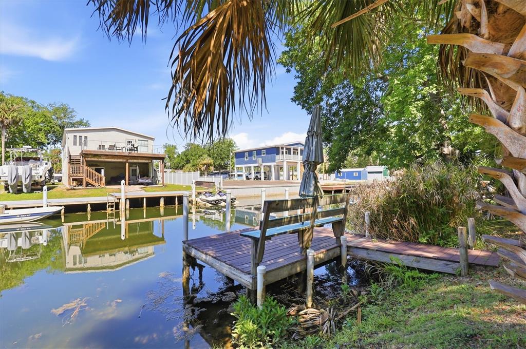 A wooden dock with a bench sits on a canal in front of waterfront houses — 6169 WAVERLY ROAD, WEEKI WACHEE, FL