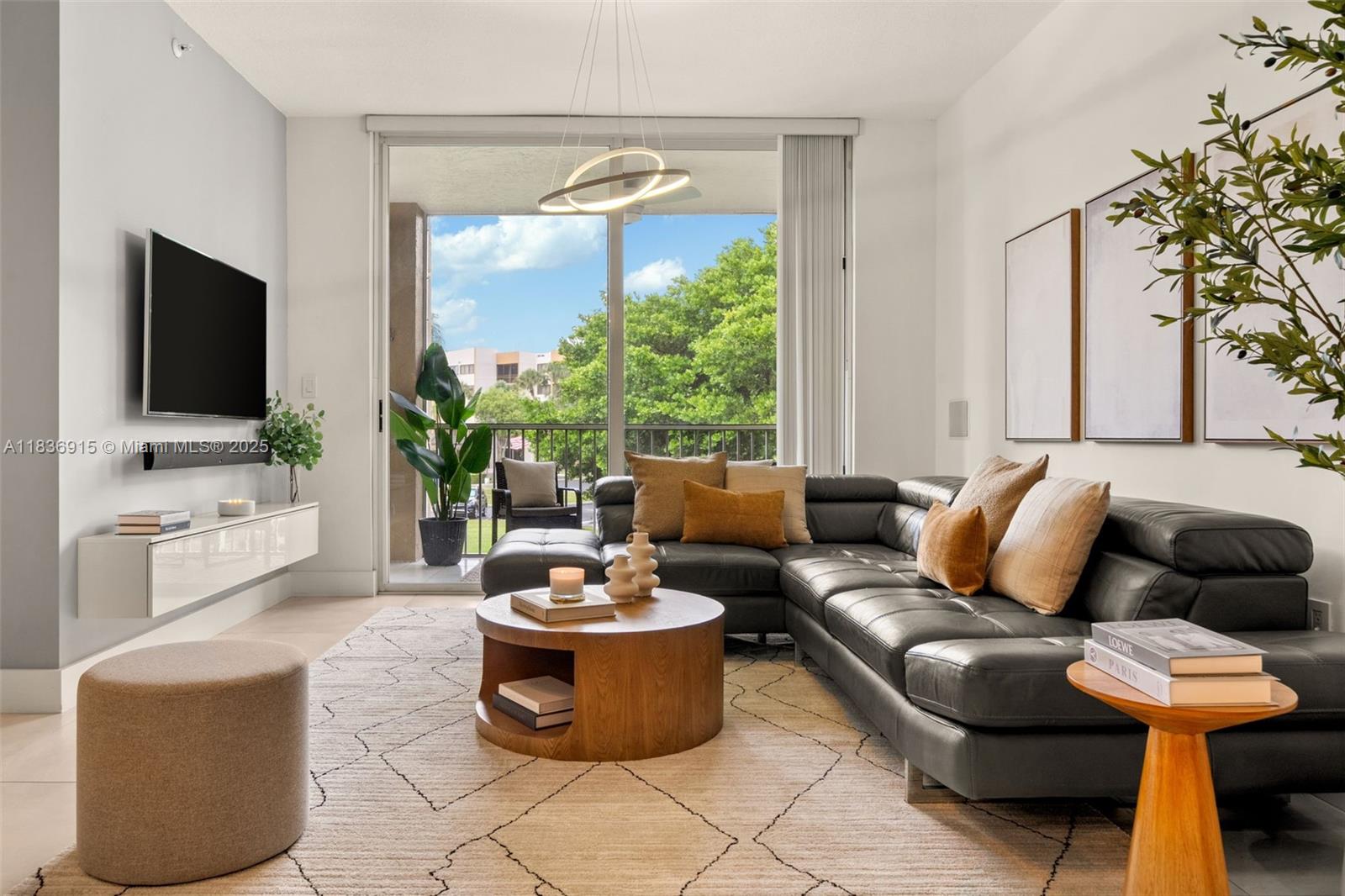 A modern living room features a dark leather sectional, round wooden coffee table, and balcony access — 9755 NW 52nd St # 206, Doral FL 33178, DORAL, FL