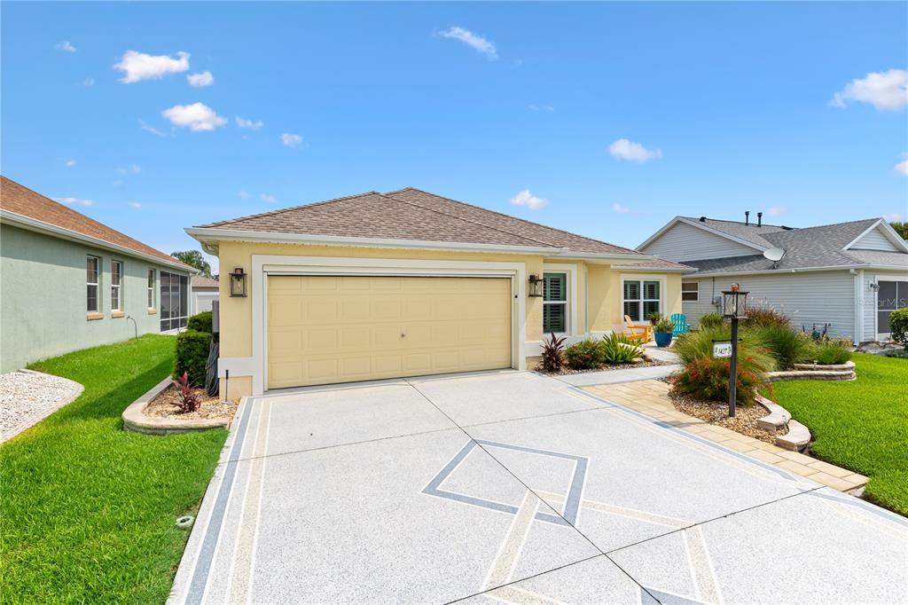 A single-story house with a yellow exterior, a two-car garage, and a patterned concrete driveway — 1427 GAYLE MILL DRIVE, THE VILLAGES, FL