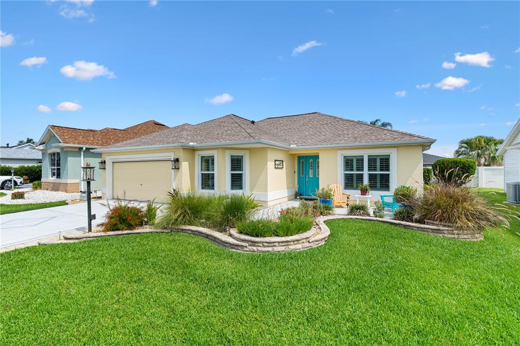 A single-story house with a yellow exterior, a two-car garage, and a landscaped front yard — 1427 GAYLE MILL DRIVE, THE VILLAGES, FL